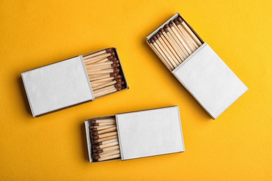 Photo of Cardboard boxes with matches on color background, flat lay. Space for design