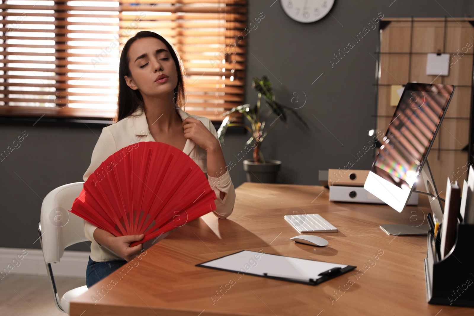 Photo of Woman with hand fan suffering from heat at home. Summer season