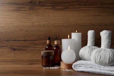 Photo of Beautiful spa composition with different care products and burning candles on wooden table. Space for text