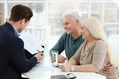Photo of Mature couple discussing pension with consultant in office