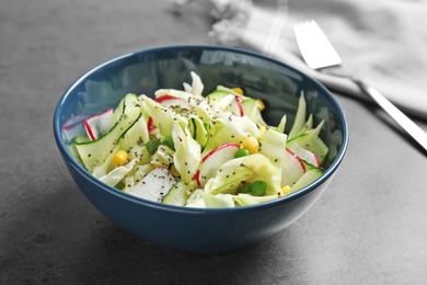 Photo of Bowl with healthy cabbage salad on dark table