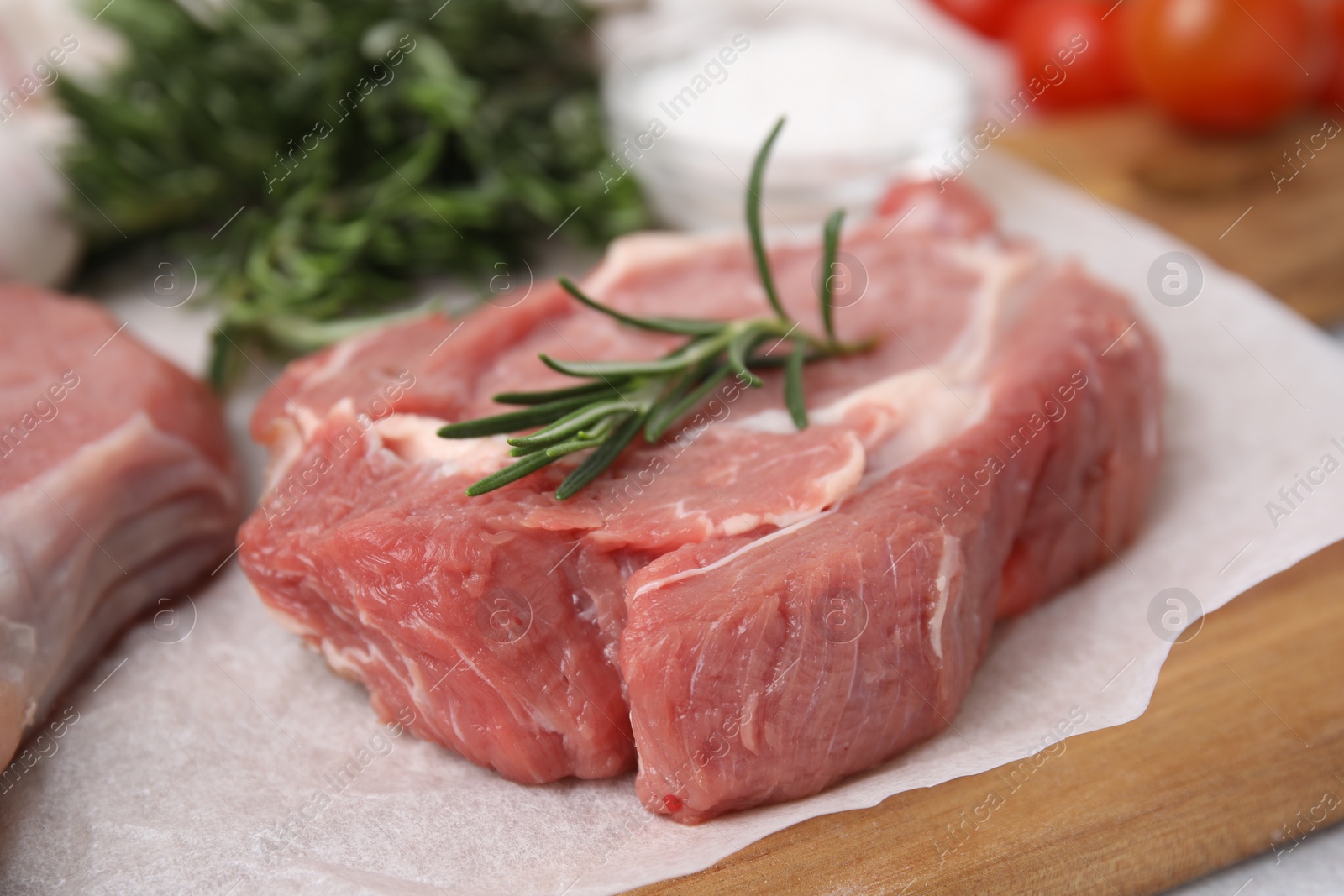 Photo of Fresh raw meat with rosemary on wooden board, closeup