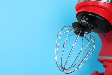 Closeup view of modern red stand mixer on turquoise background, space for text