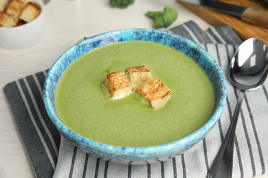 Photo of Delicious broccoli cream soup with croutons served on table