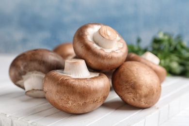 Fresh champignon mushrooms on wooden board, closeup