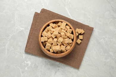 Photo of Brown sugar cubes on light grey marble table, flat lay