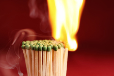 Photo of Group of burning matchsticks on red background, closeup