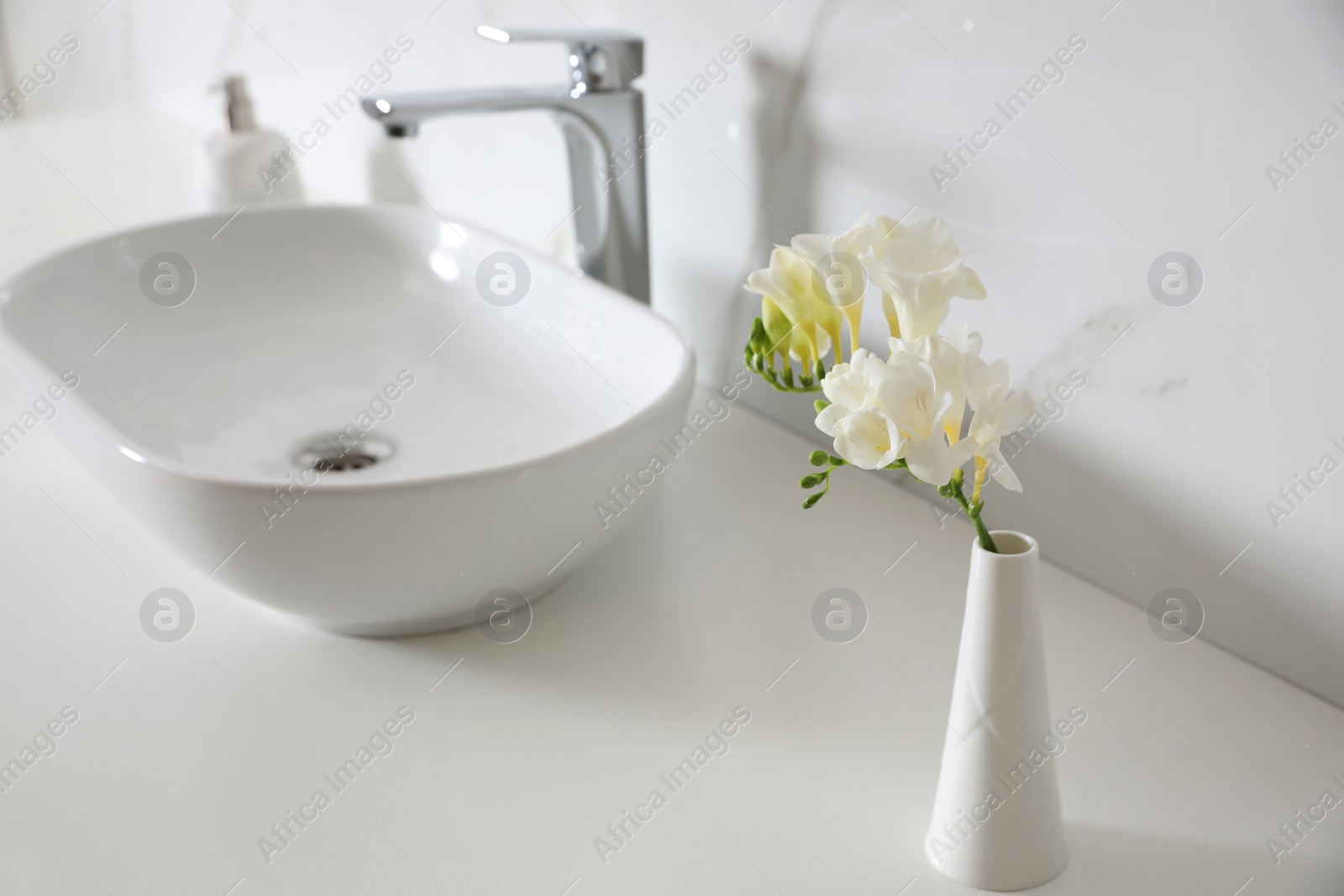 Photo of Beautiful bouquet with white freesia flowers in bathroom, space for text