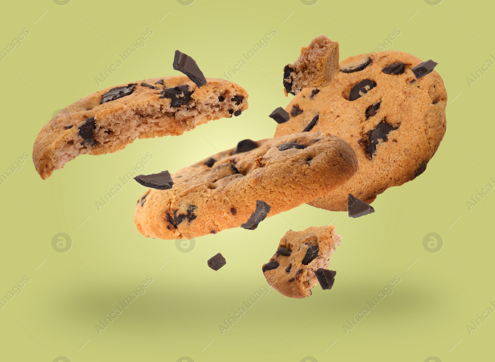 Image of Tasty chocolate chip cookies falling on light yellow green background