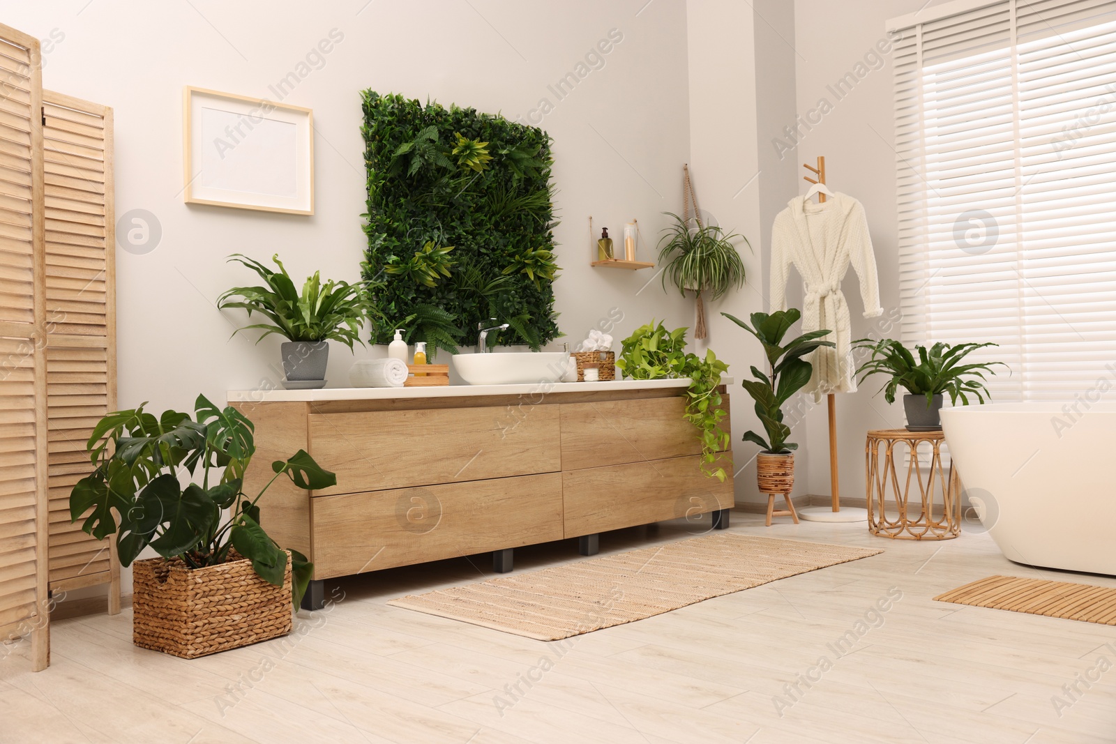 Photo of Green artificial plants, vanity and different personal care products in bathroom