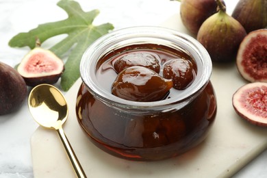 Photo of Jar of tasty sweet jam and fresh figs on white marble table