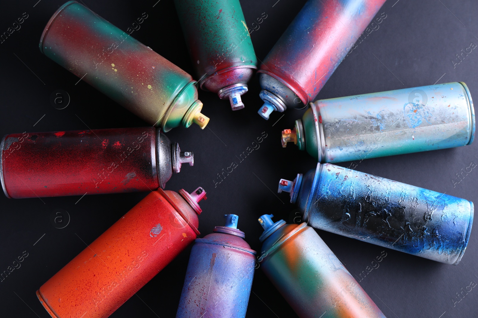 Photo of Many spray paint cans on black background, top view