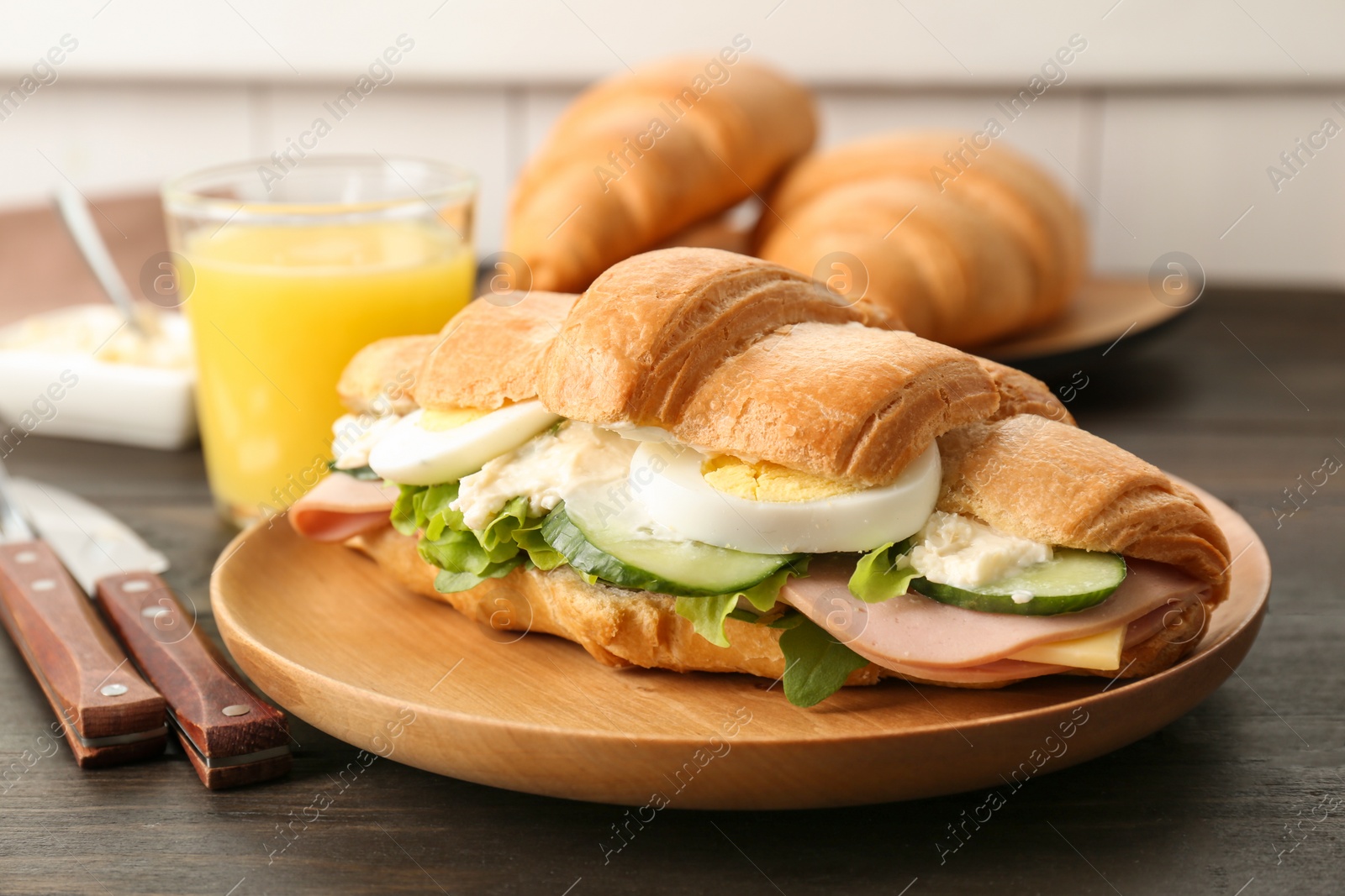 Photo of Tasty croissant sandwich with sausage on table