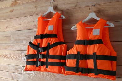 Photo of Orange life jackets on wooden background. Personal flotation device