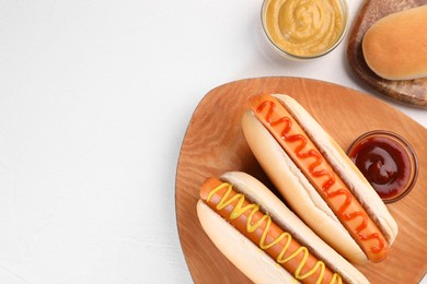 Photo of Tasty hot dogs with ketchup and mustard on white table, flat lay. Space for text