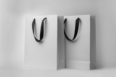 Photo of Paper shopping bags with ribbon handles on white background. Mockup for design