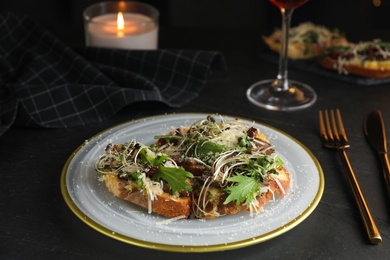 Photo of Delicious bruschettas with beef and cheese on black table