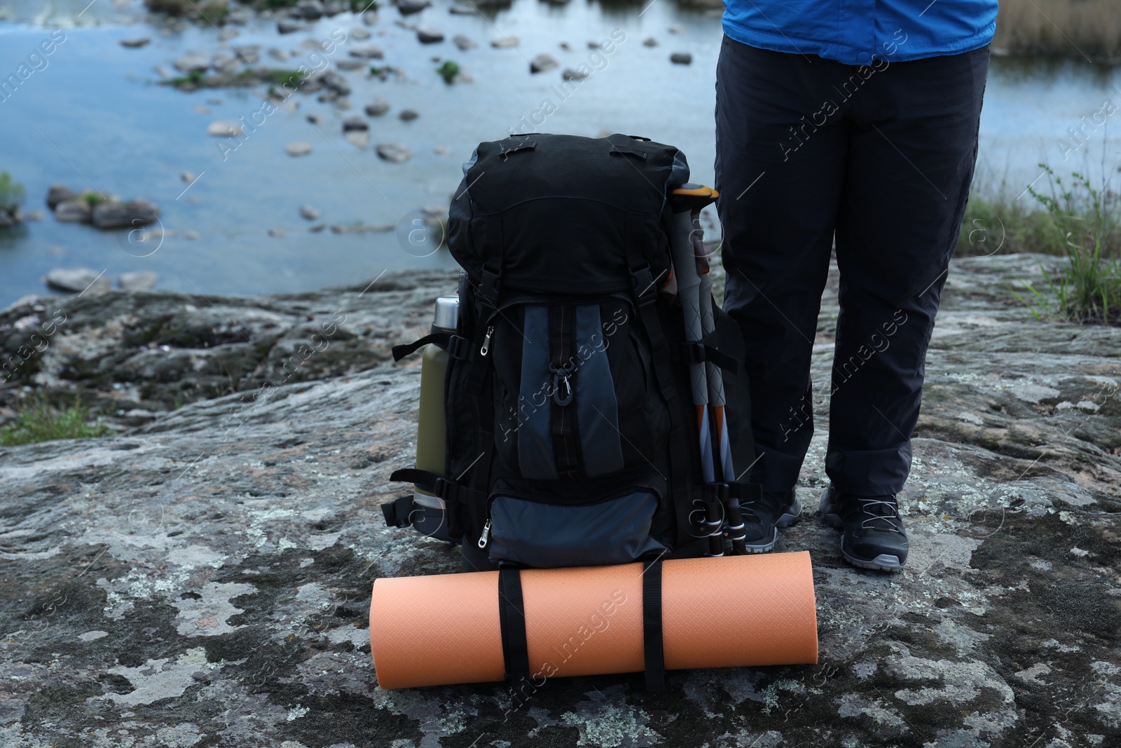 Photo of Hiker with backpack ready for journey on rock near river, closeup