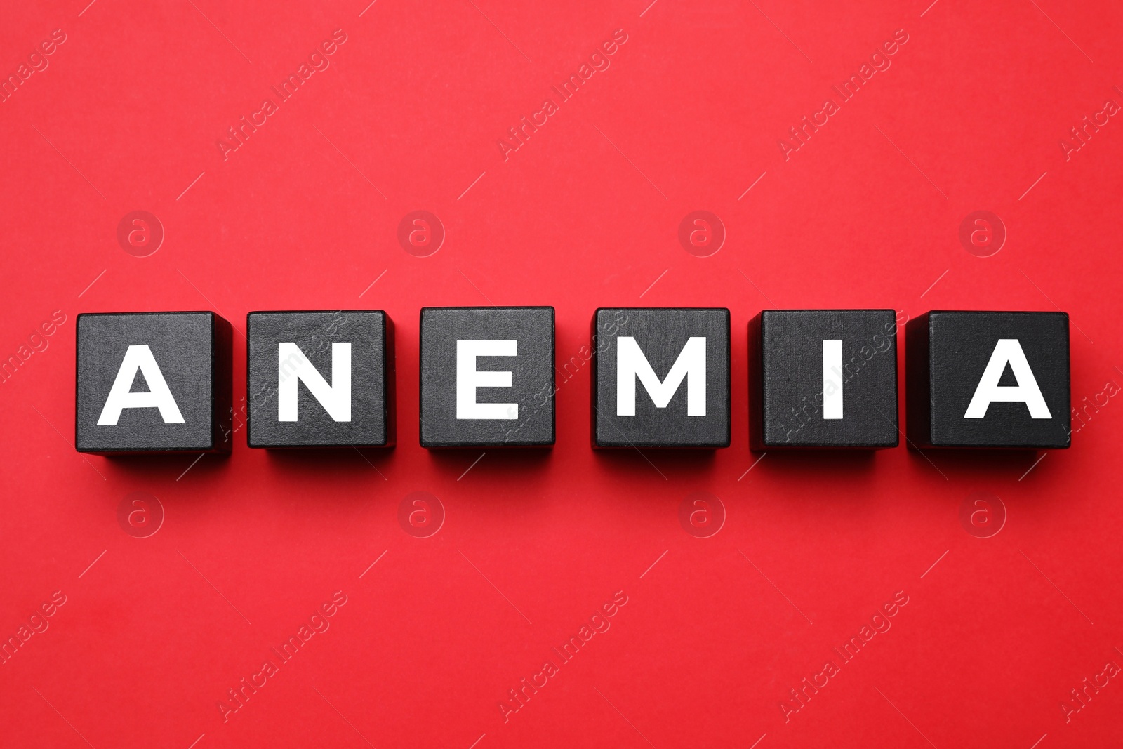 Photo of Wooden cubes with word Anemia on red background, flat lay