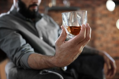 Photo of Man with glass of whiskey indoors, closeup