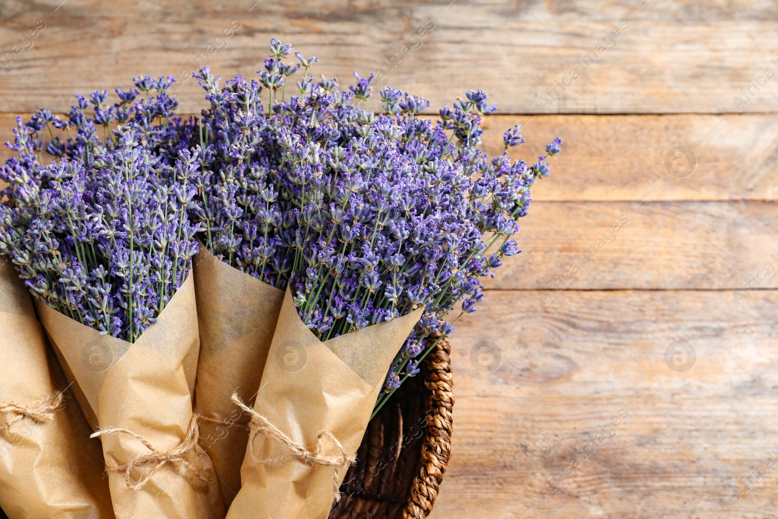 Photo of Fresh lavender flowers in basket on wooden table, top view. Space for text