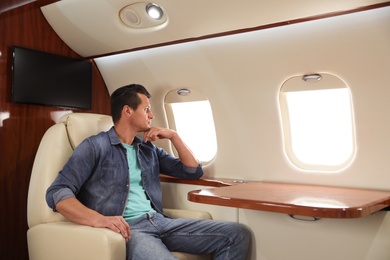 Handsome man looking out of airplane window. Comfortable flight