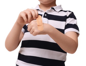 Photo of Little boy putting sticking plaster onto hand on white background, closeup