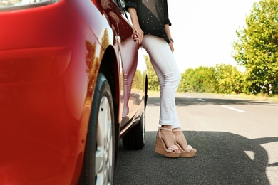 Photo of Young woman near car outdoors on sunny day, closeup of legs