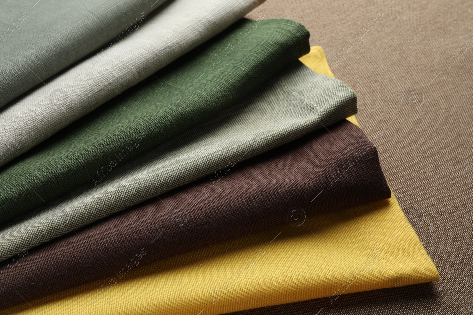 Photo of Many different color fabrics on brown cloth, closeup
