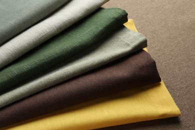 Photo of Many different color fabrics on brown cloth, closeup