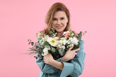 Beautiful woman with bouquet of flowers on pink background