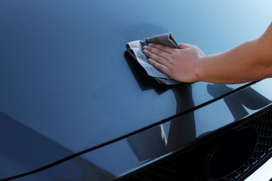 Man cleaning car hood with rag, closeup