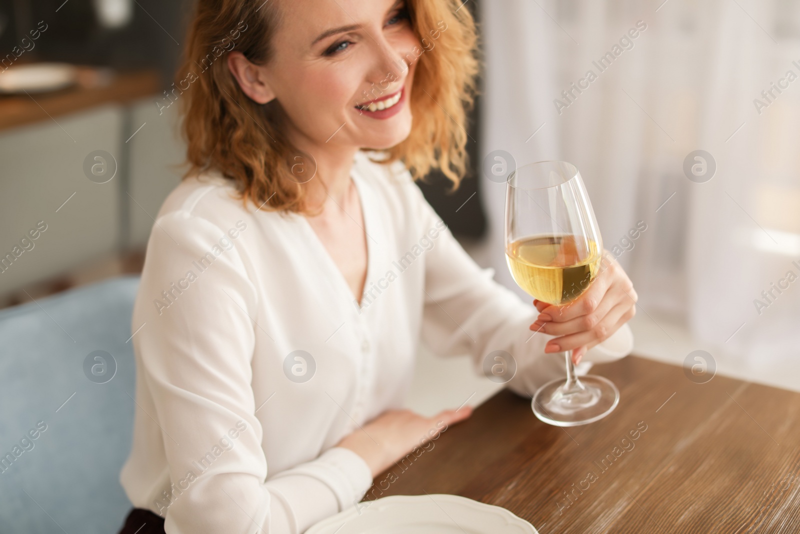 Photo of Woman with glass of wine at table in restaurant