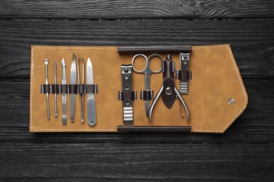 Manicure set in case on black wooden table, top view