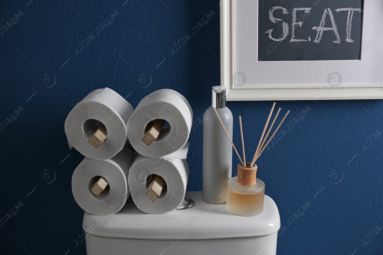 Photo of Decor elements, necessities and toilet bowl near blue wall. Bathroom interior