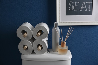 Photo of Decor elements, necessities and toilet bowl near blue wall. Bathroom interior