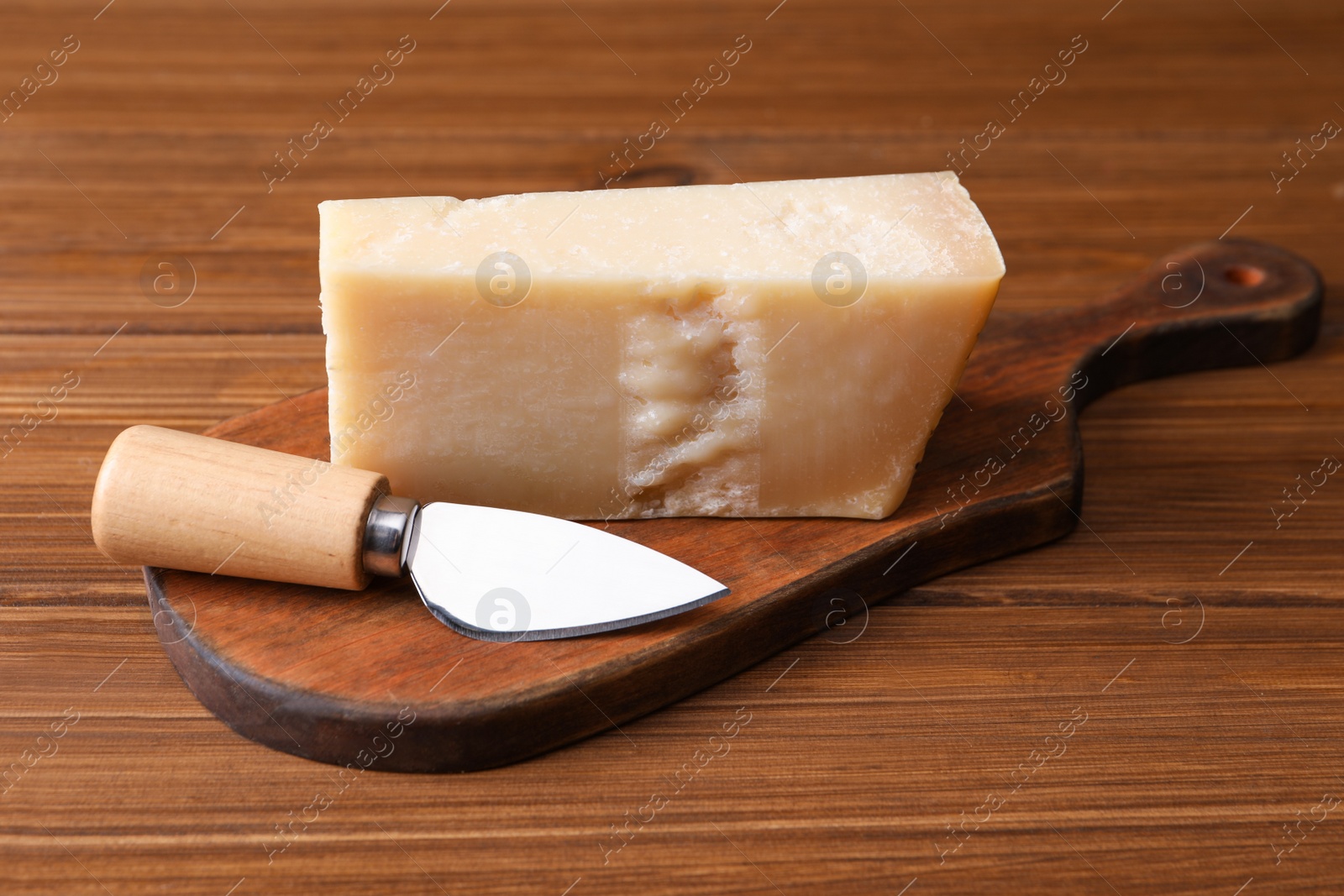 Photo of Delicious parmesan cheese with knife on wooden table