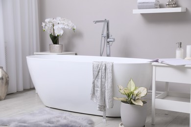 Photo of White tub and beautiful plants in bathroom, Interior design