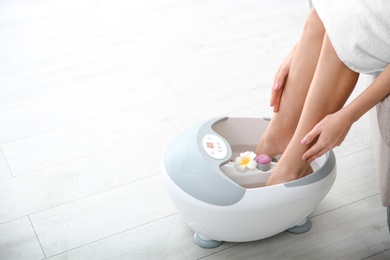 Photo of Woman with beautiful legs using foot bath at home, closeup with space for text. Spa treatment