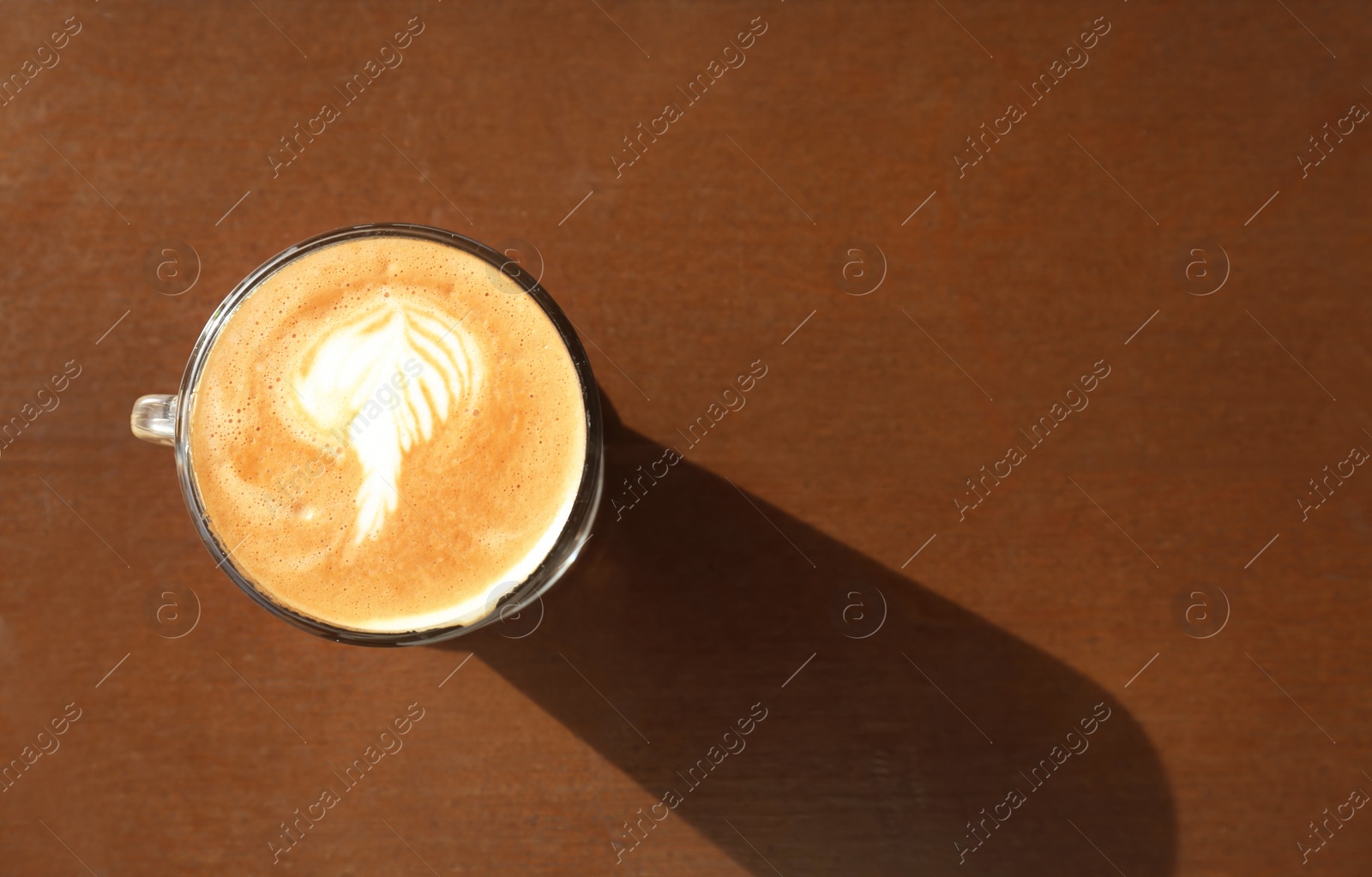 Photo of Cup of aromatic coffee with foam on wooden table, top view