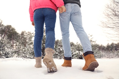 Photo of Couple walking in snowy forest on winter day, closeup