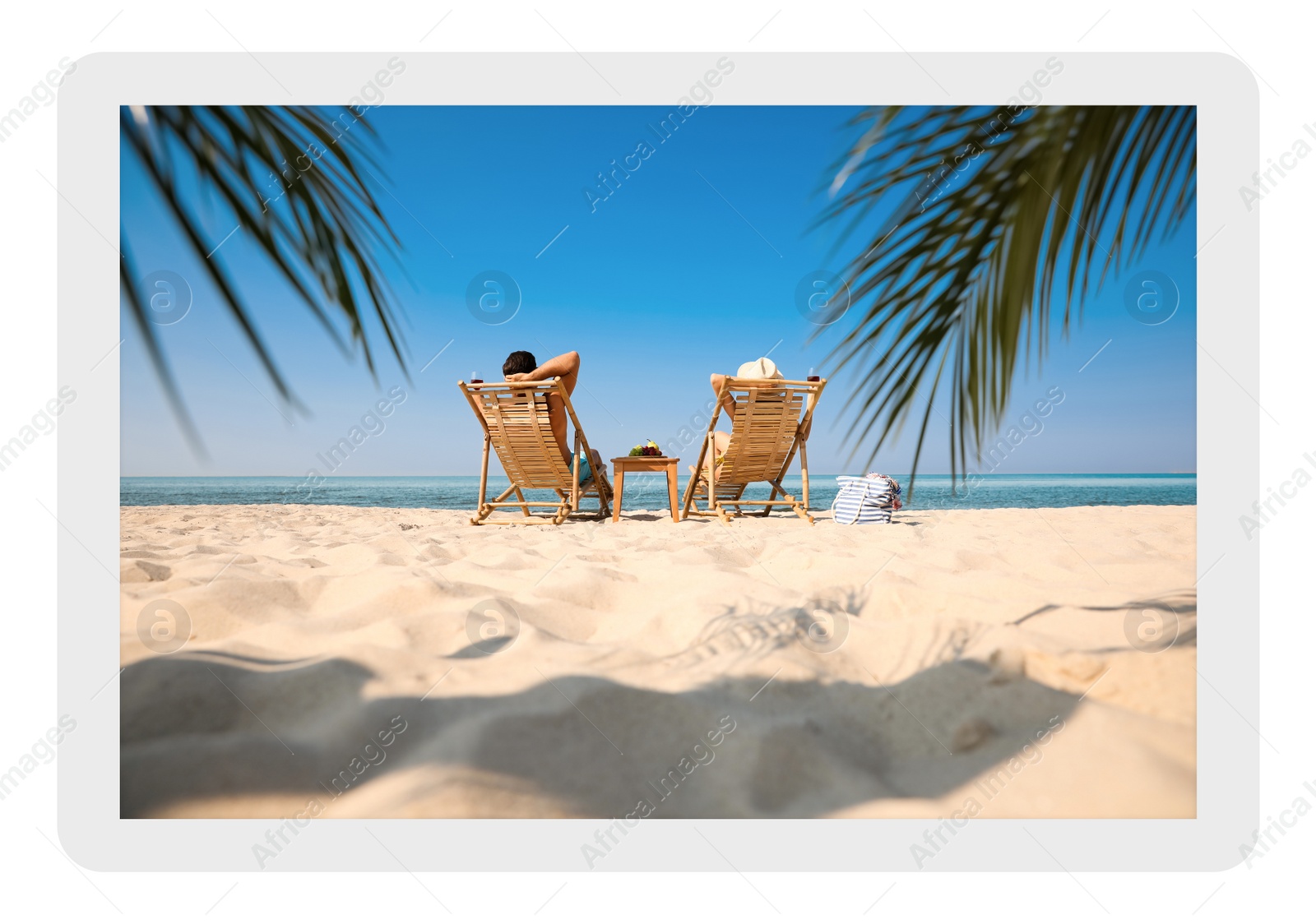 Image of Paper photo. Couple with wine on sandy beach at resort