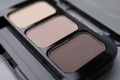 Photo of Beautiful eyeshadow palette on light gray background, closeup. Professional cosmetic product