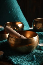 Tibetan singing bowls with mallet and candles on turquoise fabric