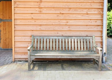 Stylish bench near wooden wall on sunny day