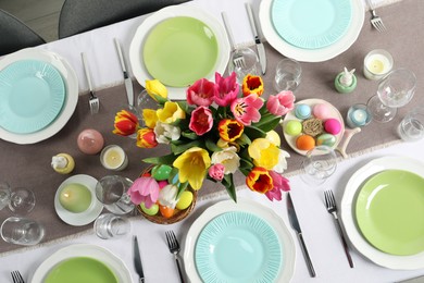 Photo of Easter celebration. Festive table setting with beautiful flowers and painted eggs, top view