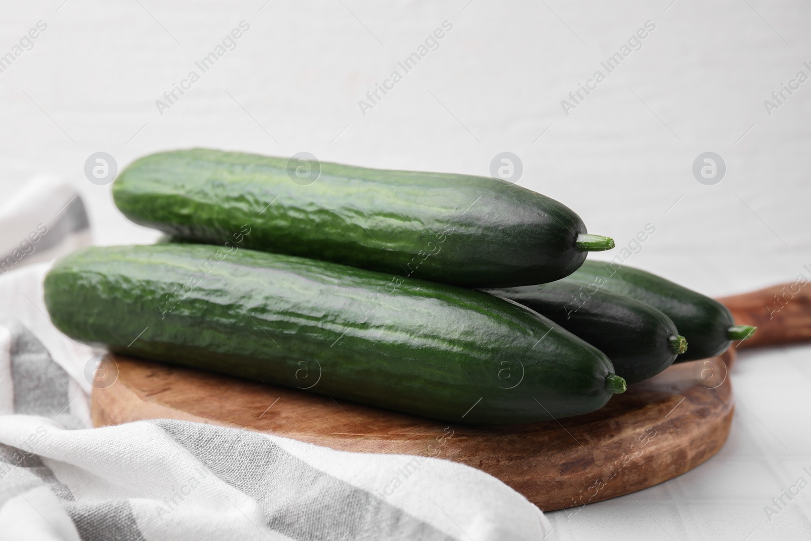 Photo of Fresh cucumbers on white tiled table, closeup