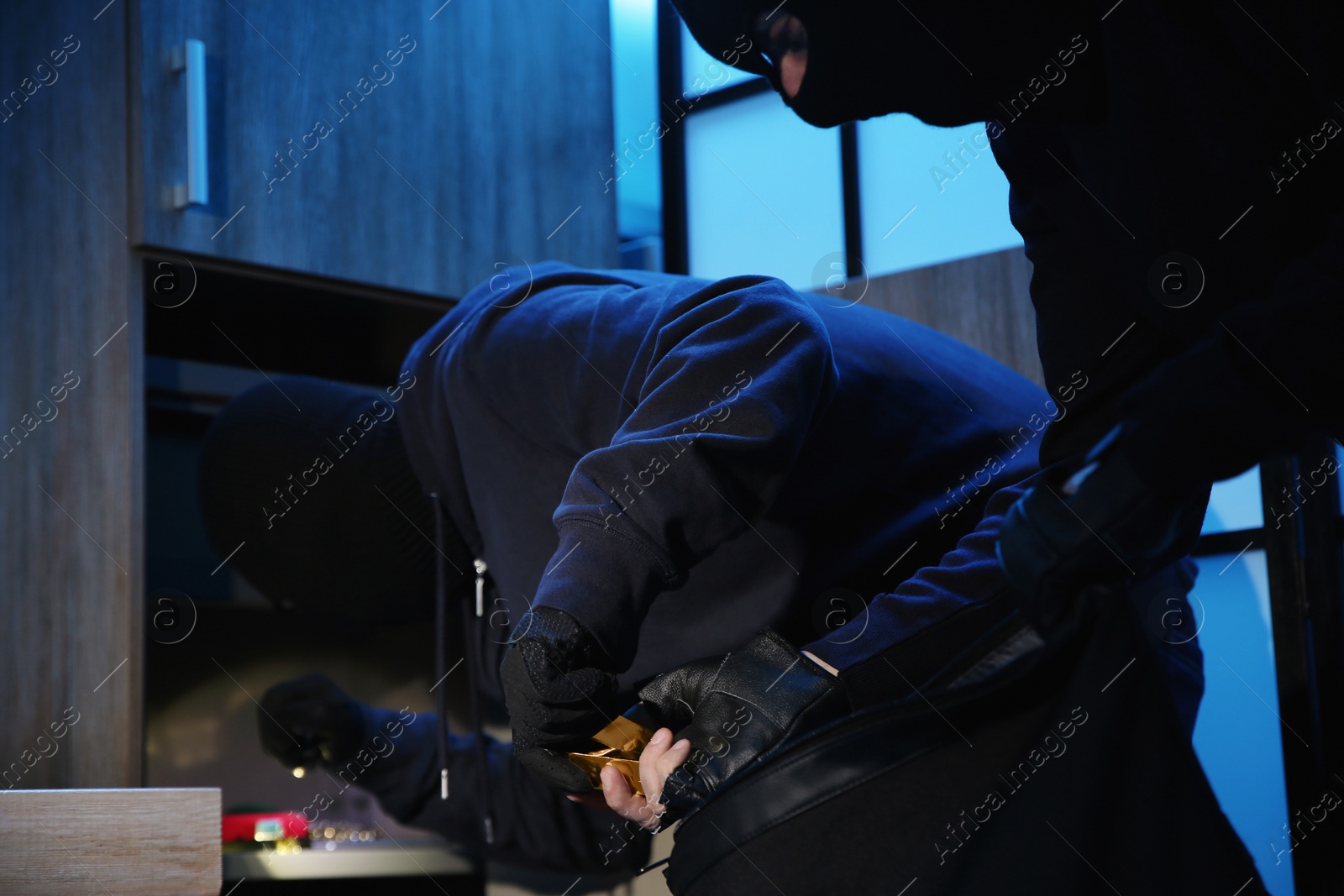 Photo of Thieves taking gold bars out of steel safe indoors at night