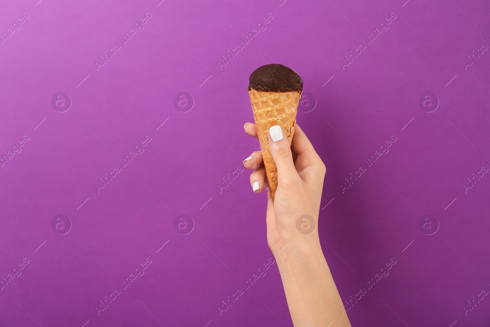 Photo of Woman holding yummy ice cream on color background. Focus on hand