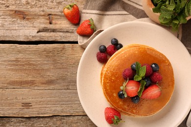 Photo of Stack of tasty pancakes with fresh berries on wooden table, flat lay. Space for text
